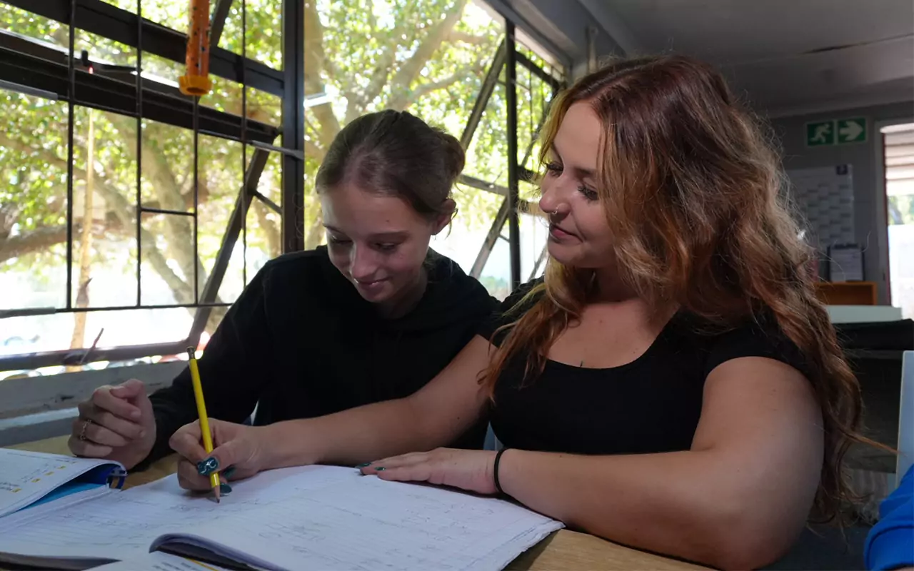 Two people working together over an open exercise book