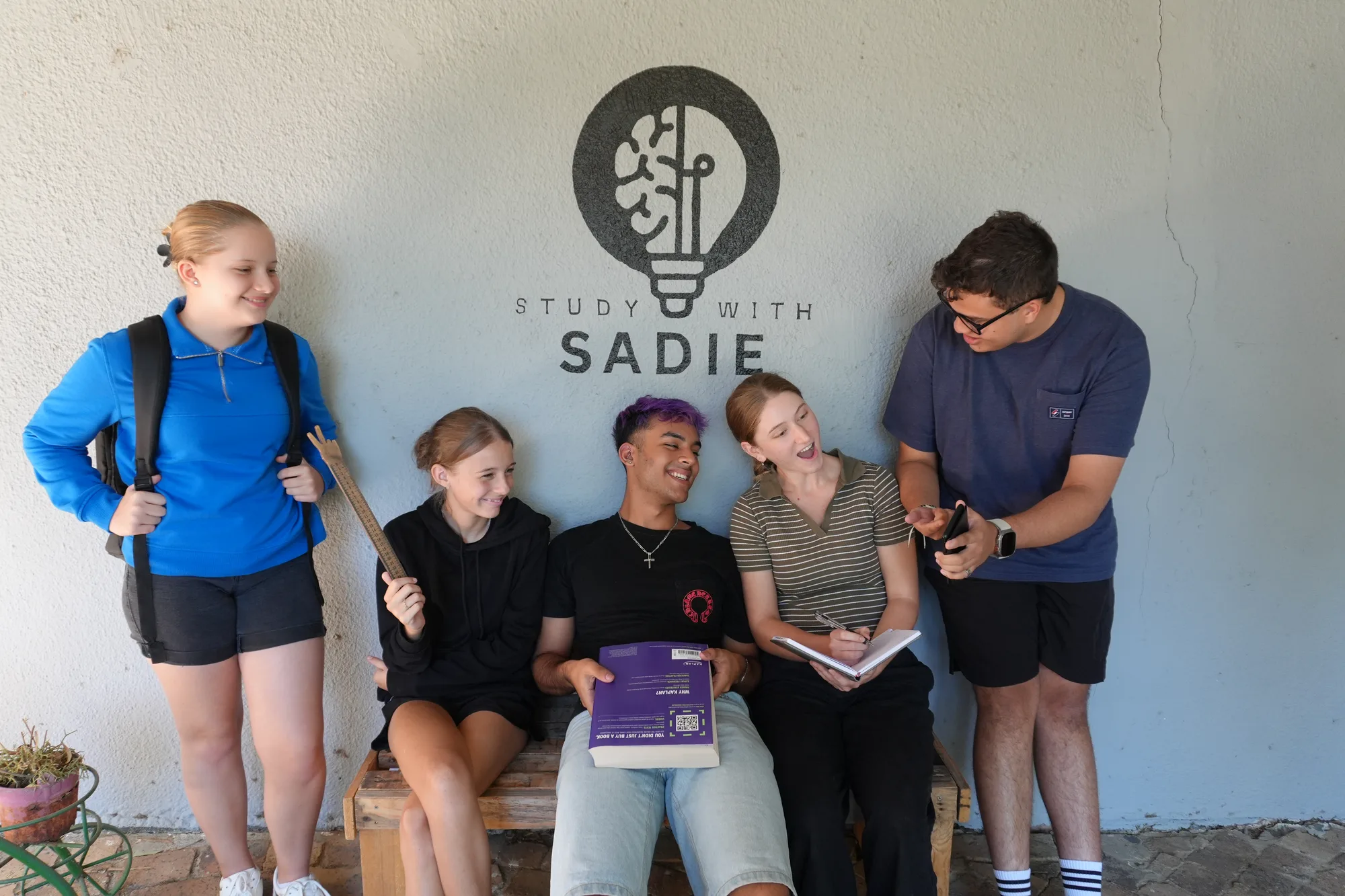 Learners sharing a relaxed moment beneath the Study With Sadie emblem