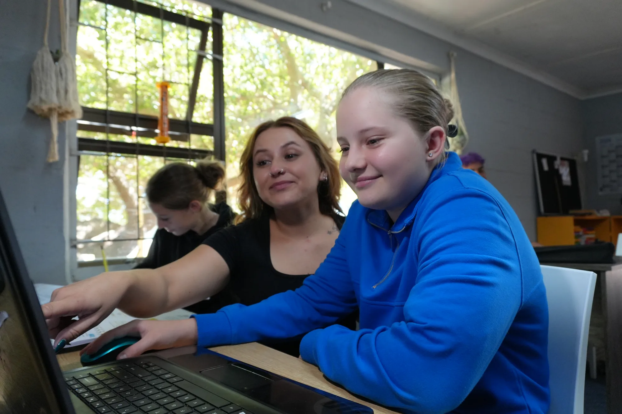 Sadie guiding a learner working on a laptop