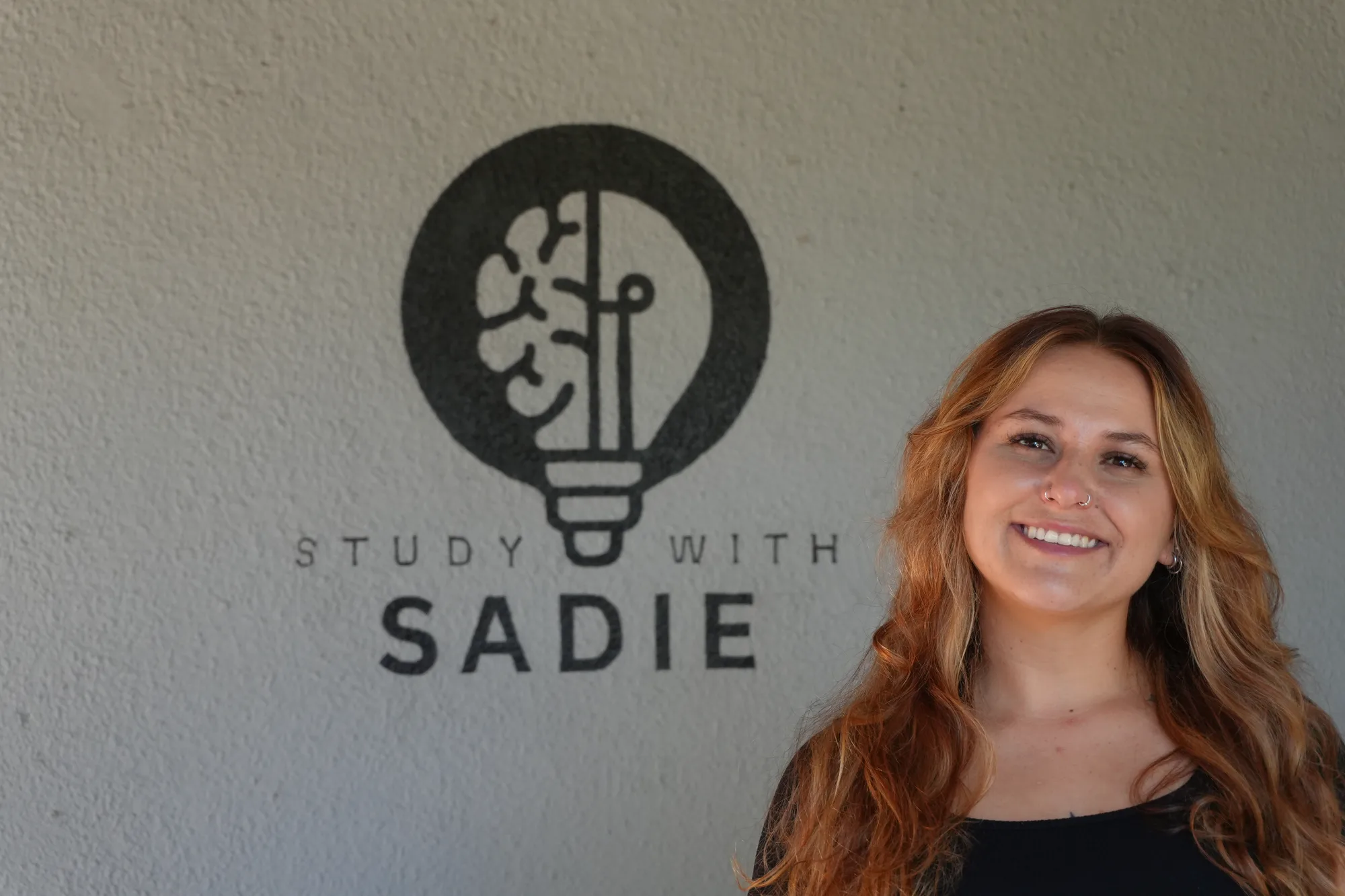 Sadie smiling beside the Study With Sadie emblem